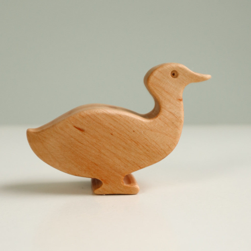 Figura de madera de un ánade real poniendo un huevo