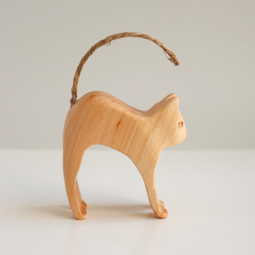 Gato encorvado sobre una figura de madera